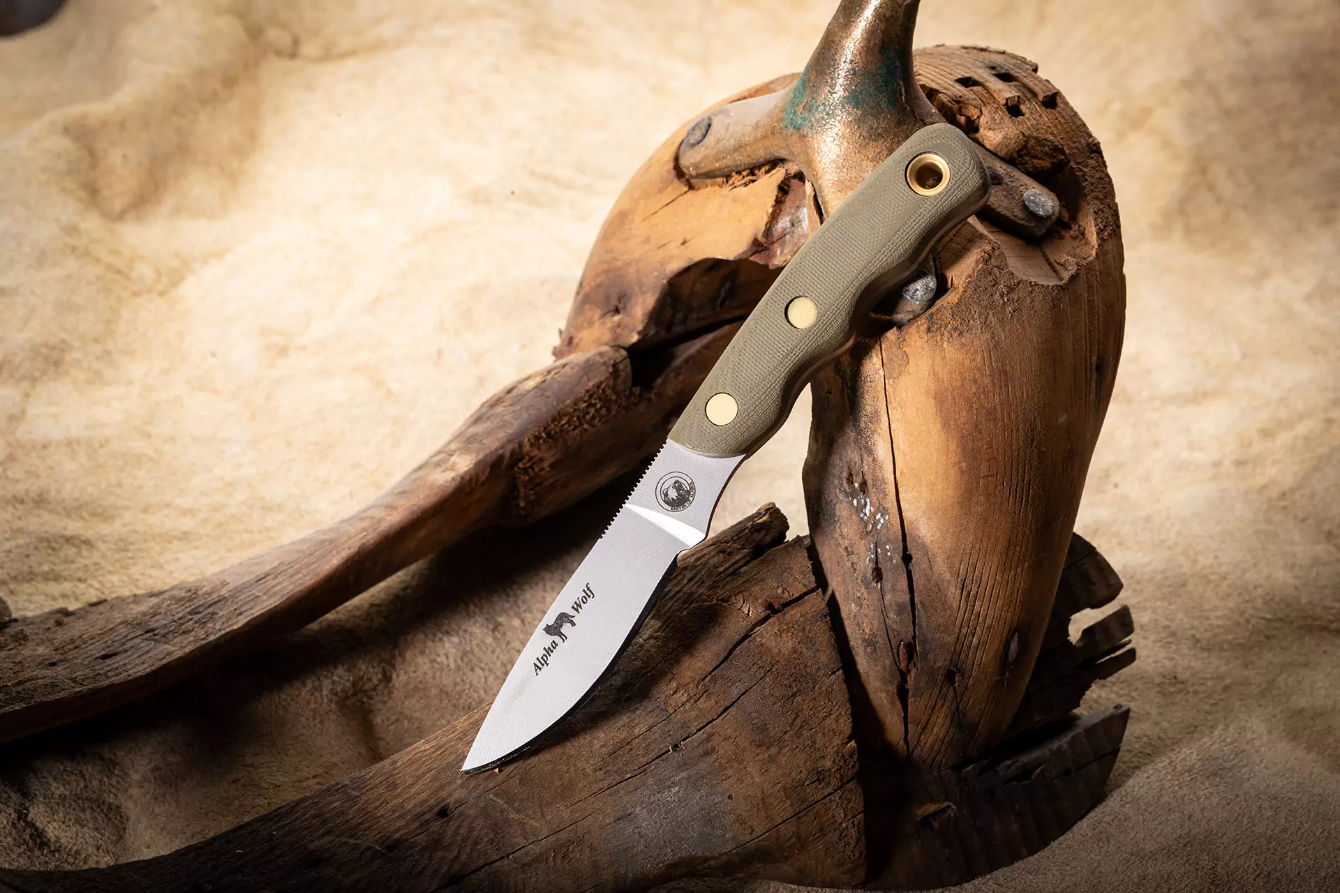 Alpha Wolf fixed-blade knife with OD green G10 handle displayed on antler and driftwood