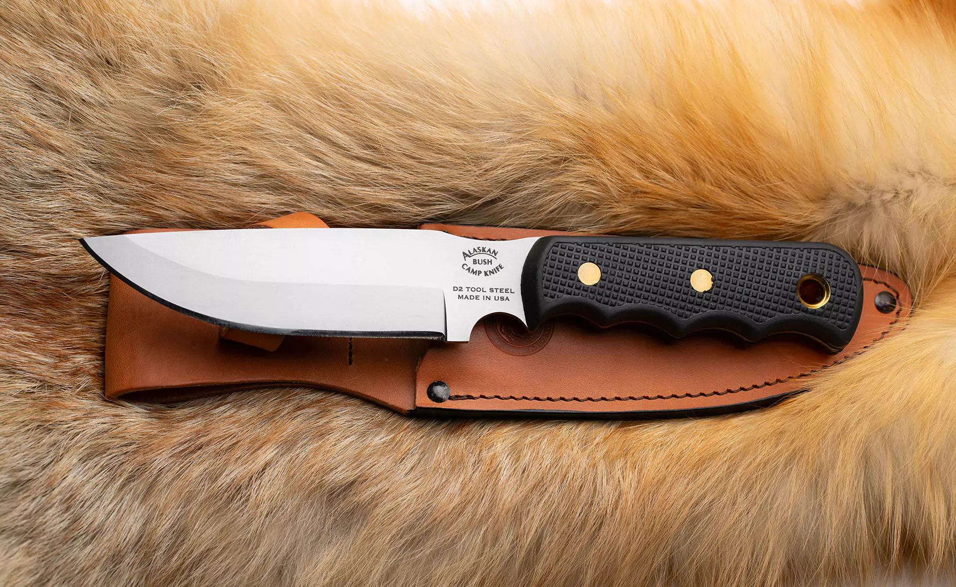 Alaskan Bush Camp Knife with Suregrip handle and leather sheath on fur background