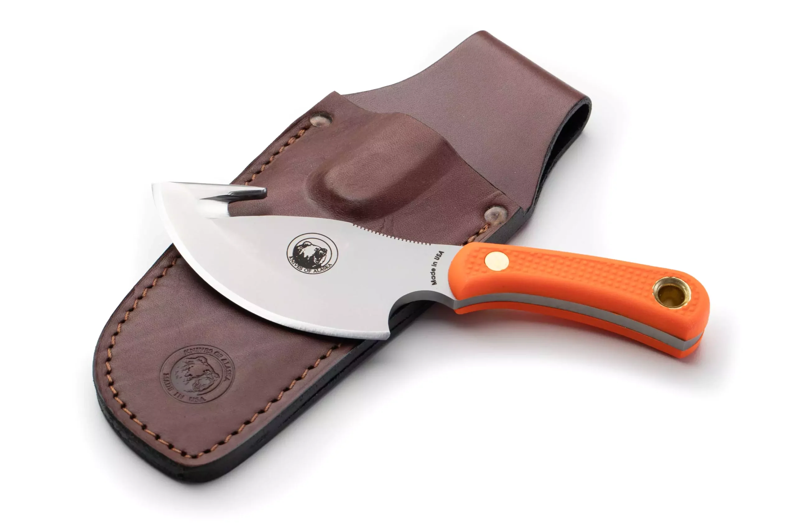 The Caribou knife with orange Suregrip handle and gut hook resting on a brown leather sheath
