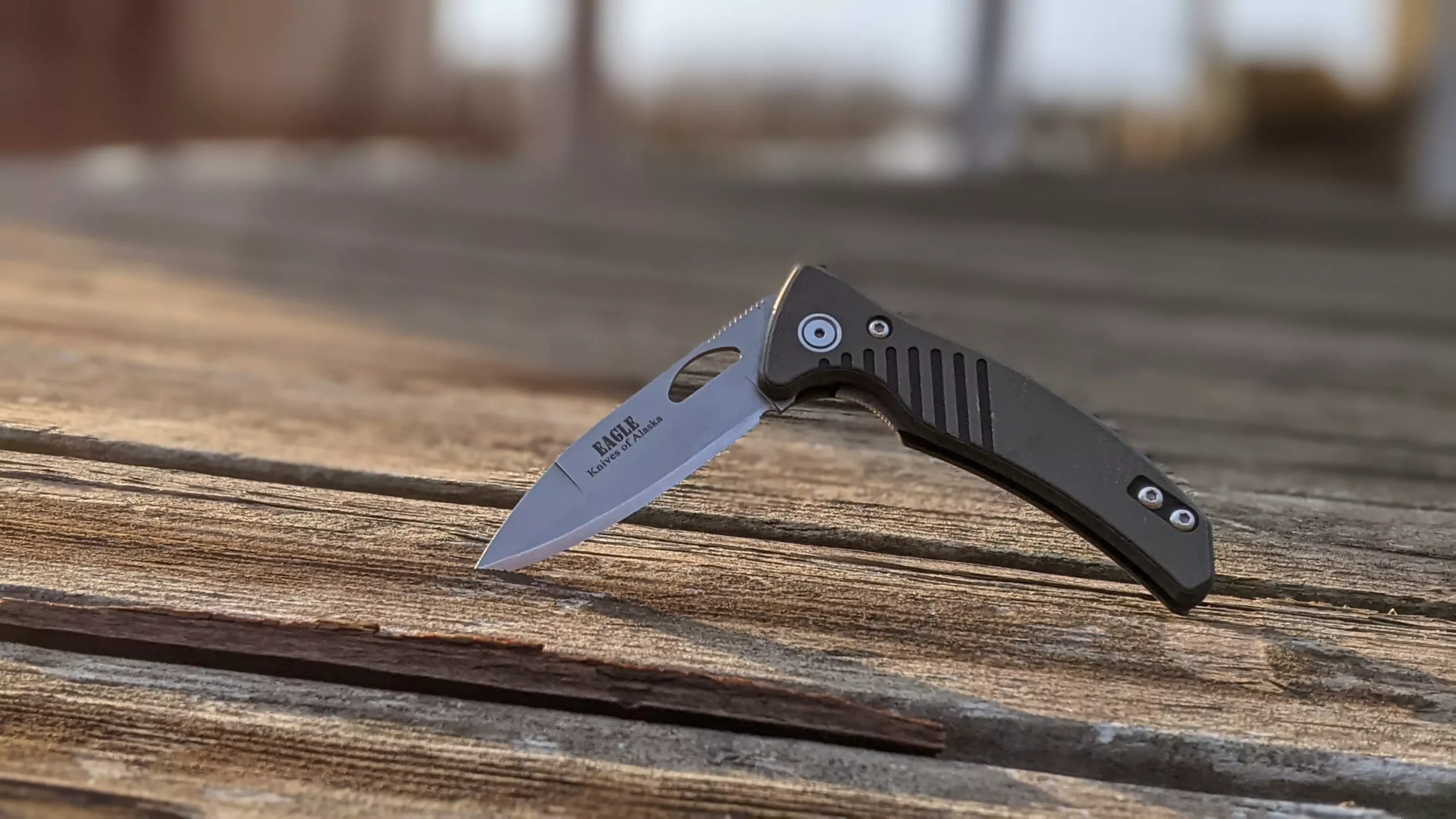 Eagle Auto folding knife with MagnaCut steel and spear-point blade on a wooden surface