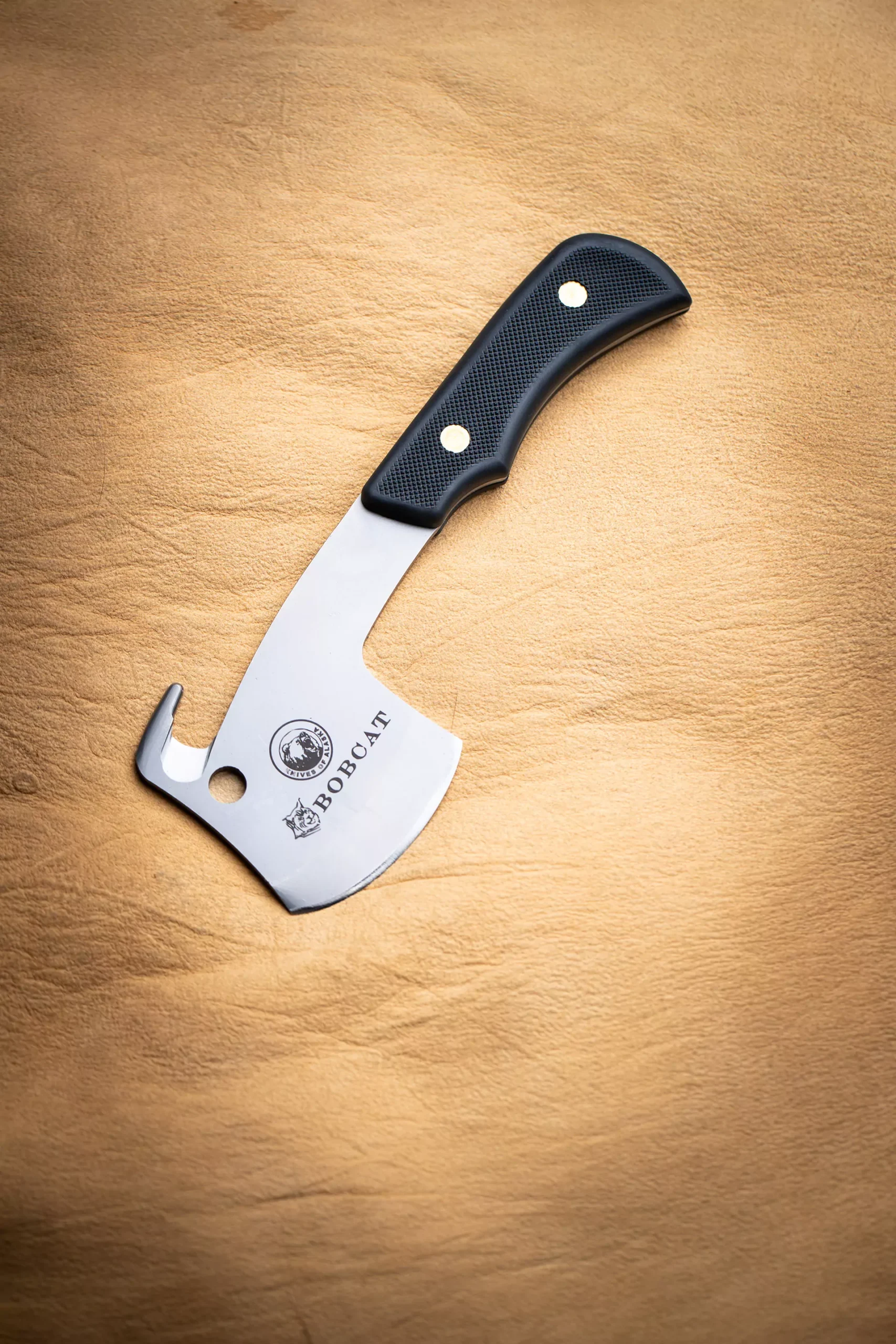 Bobcat knife with black Suregrip handle and gut hook on tan leather