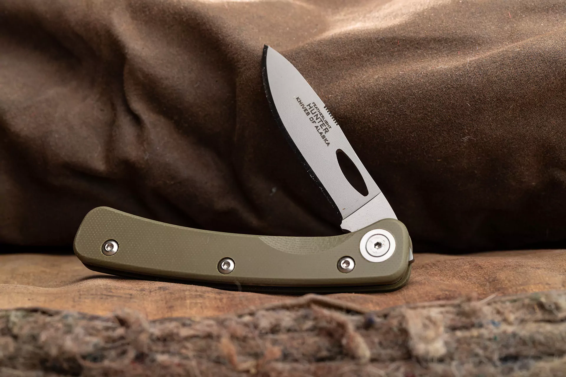 Featherlight Hunter folding knife with OD green G10 handle on waxed canvas
