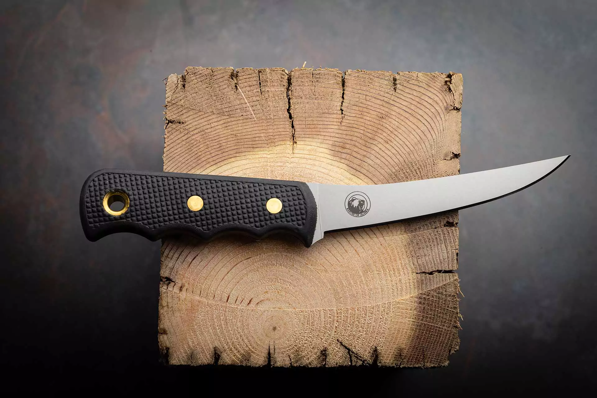 Flexible boning knife with Suregrip handle placed on a cross-cut wooden log slice