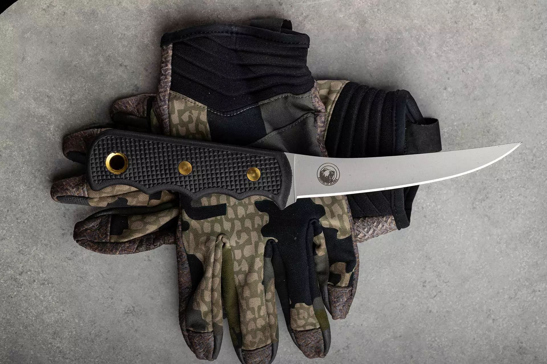 Flexible boning knife from Knives of Alaska with Suregrip handle resting on camo tactical gloves