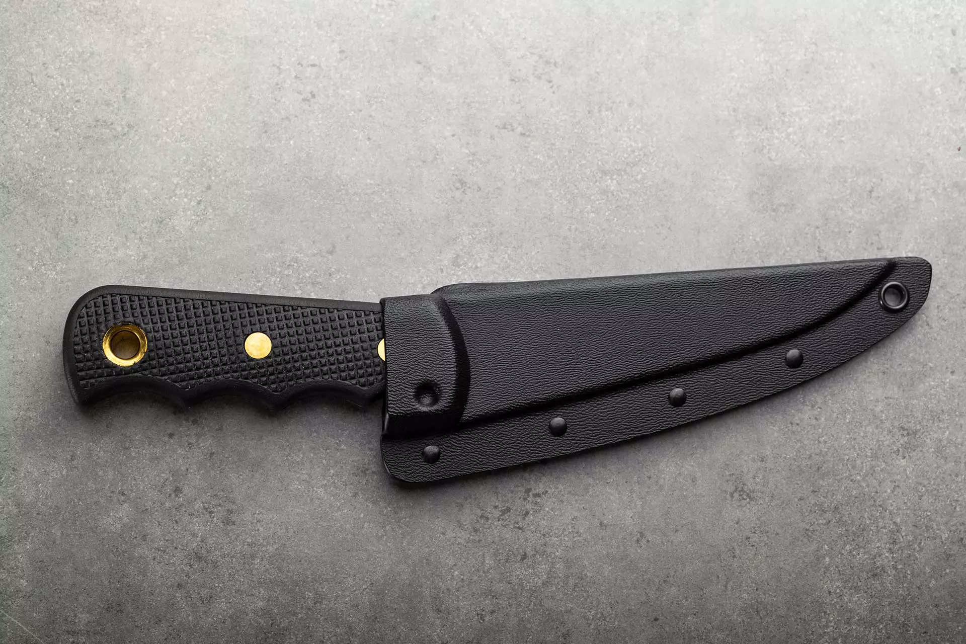 Knives of Alaska professional boning knife with Suregrip handle inside black synthetic sheath on gray background