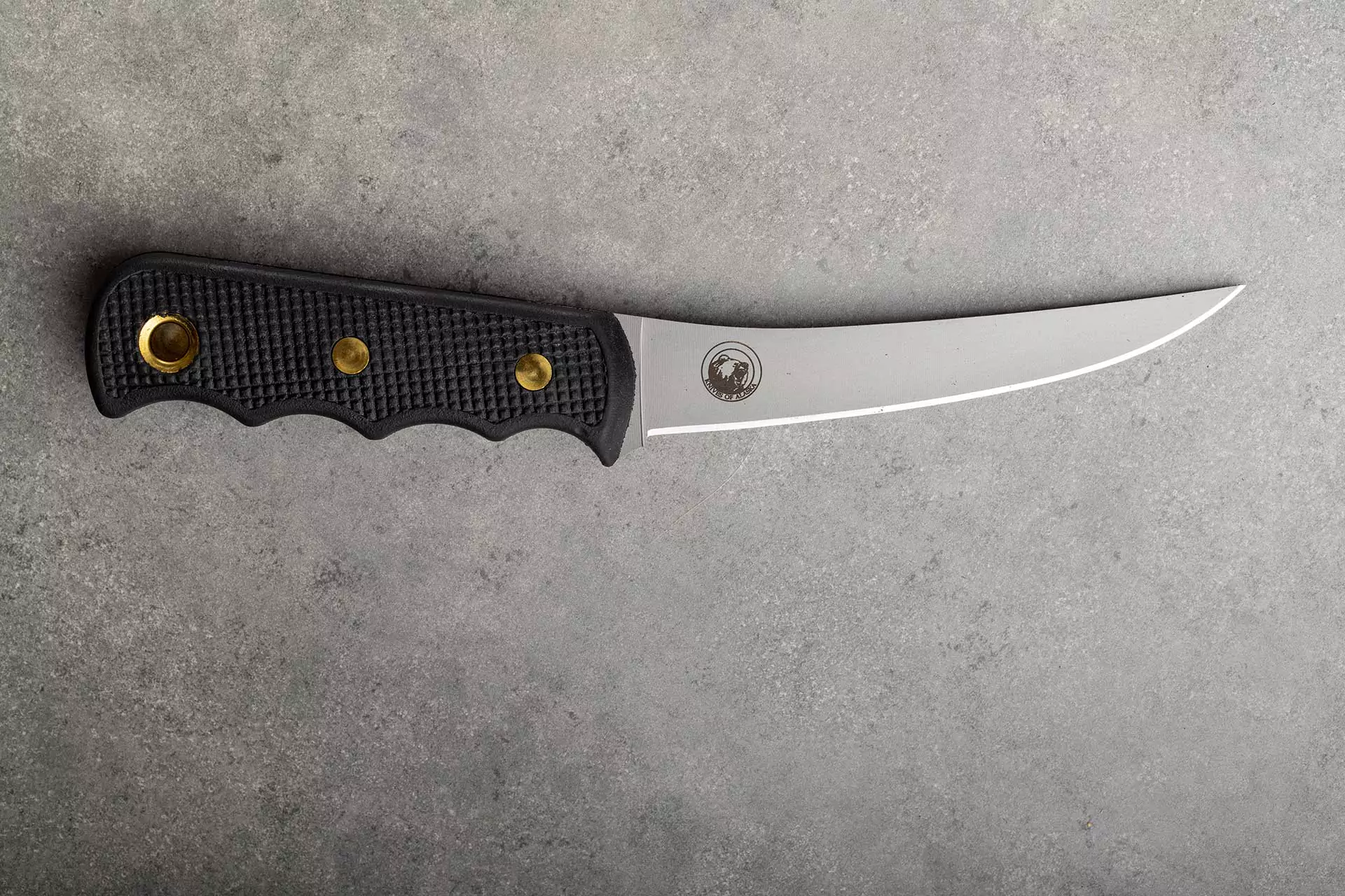 Knives of Alaska professional boning knife with black Suregrip handle and semi-flexible D2 steel blade on stone background