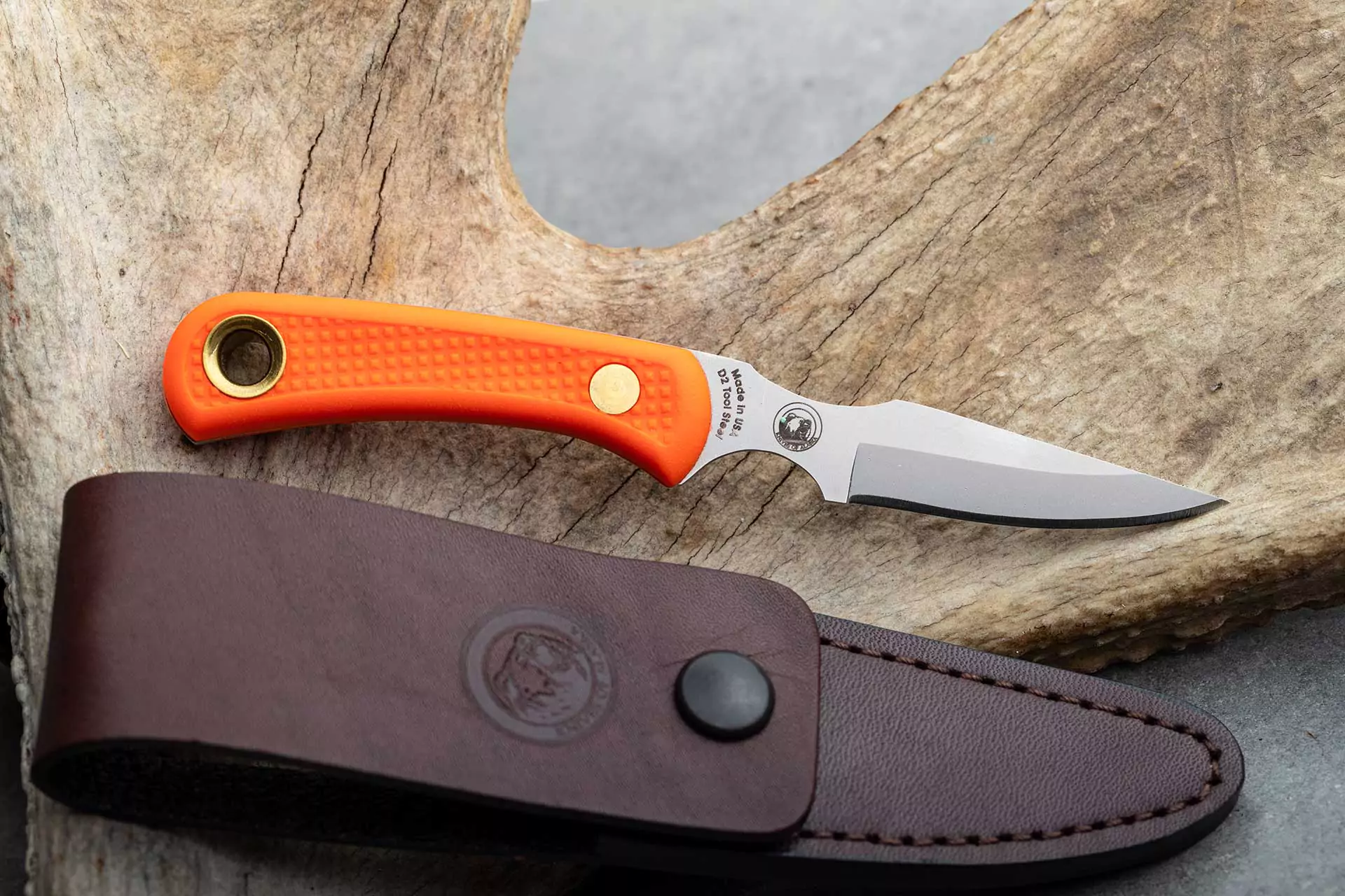 Cub Bear knife with orange Suregrip handle and leather sheath on antler