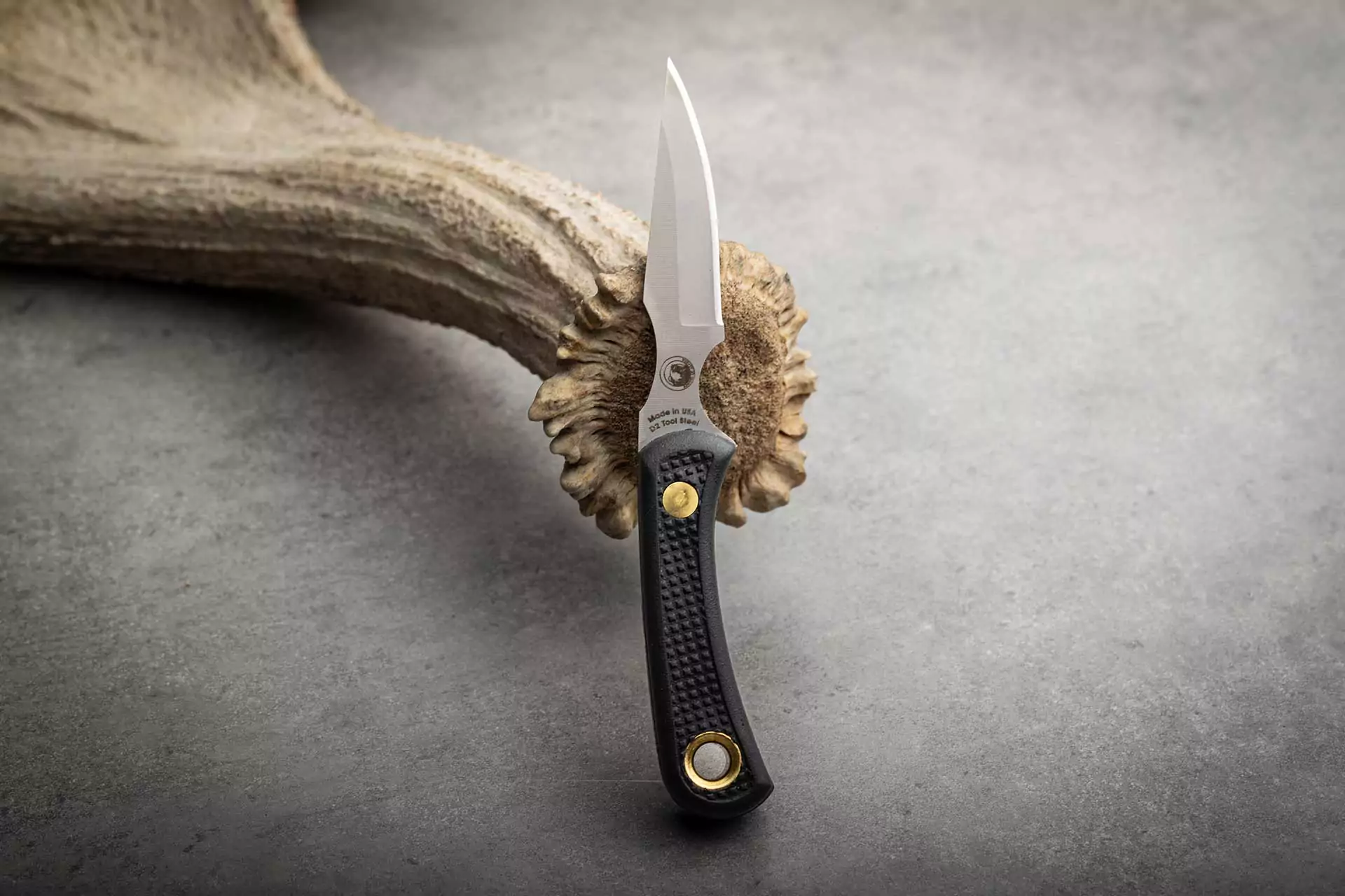 Cub Bear knife with black Suregrip handle resting on antler