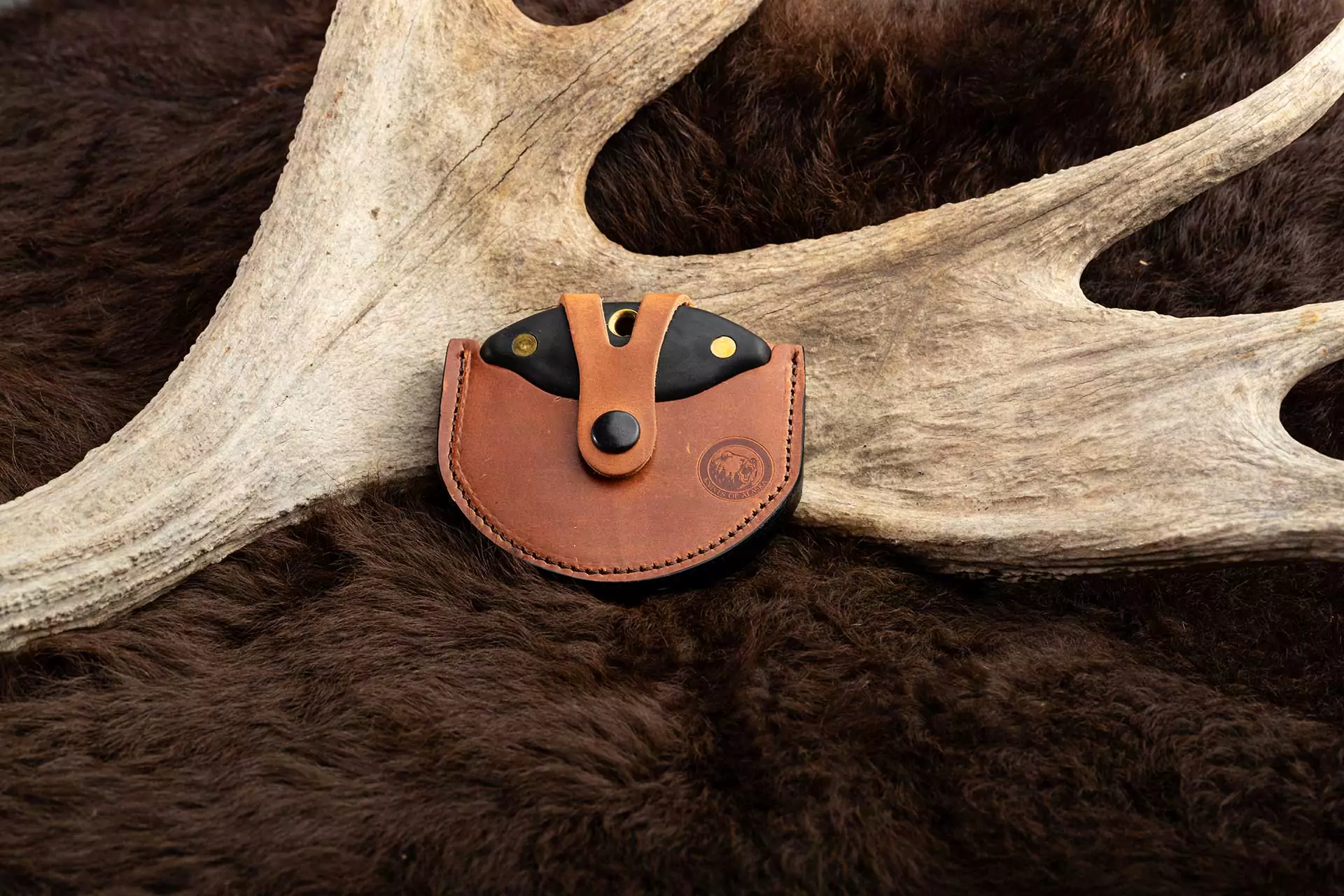 Knives of Alaska Magnum Ulu knife with black handle in leather sheath, resting on antlers and fur