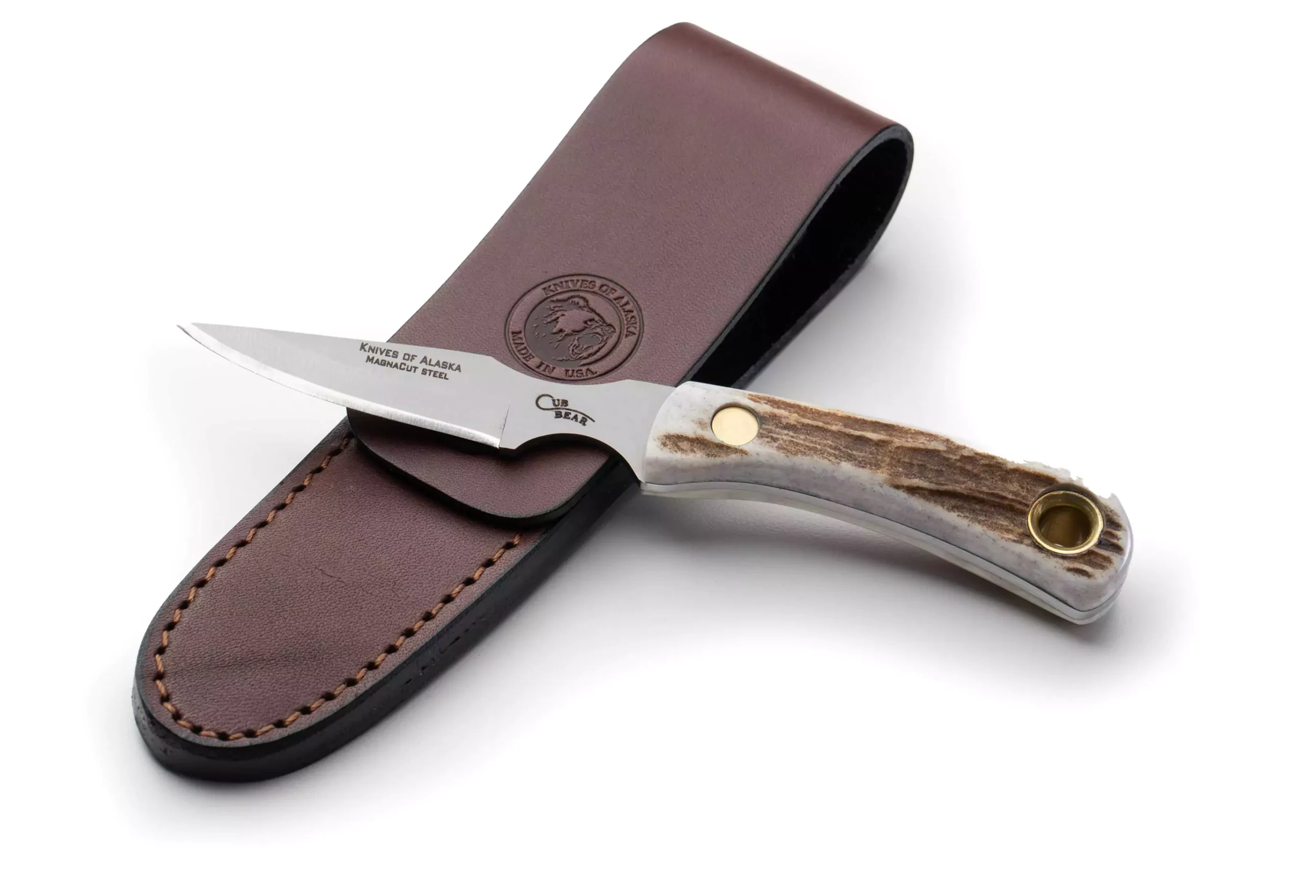 Knives of Alaska Cub Bear hunting knife with MagnaCut steel blade and stag handle resting on brown leather sheath.